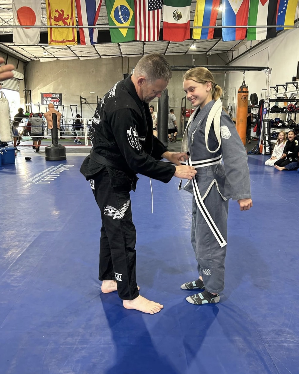 Coach tying a new belt for a young Madera Martial Arts student